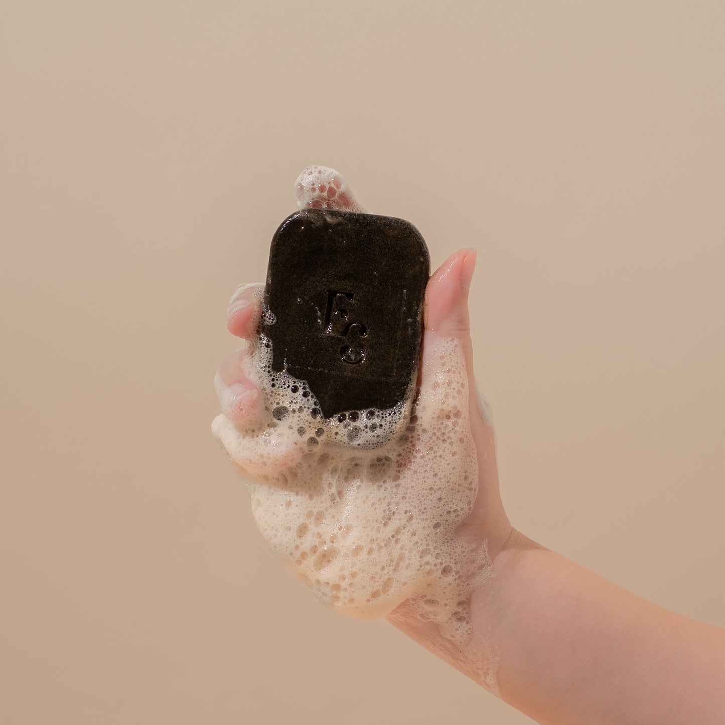 Hand holding a lathered Arabica Coffee Soap bar by Elyesence, showcasing rich foam and texture.