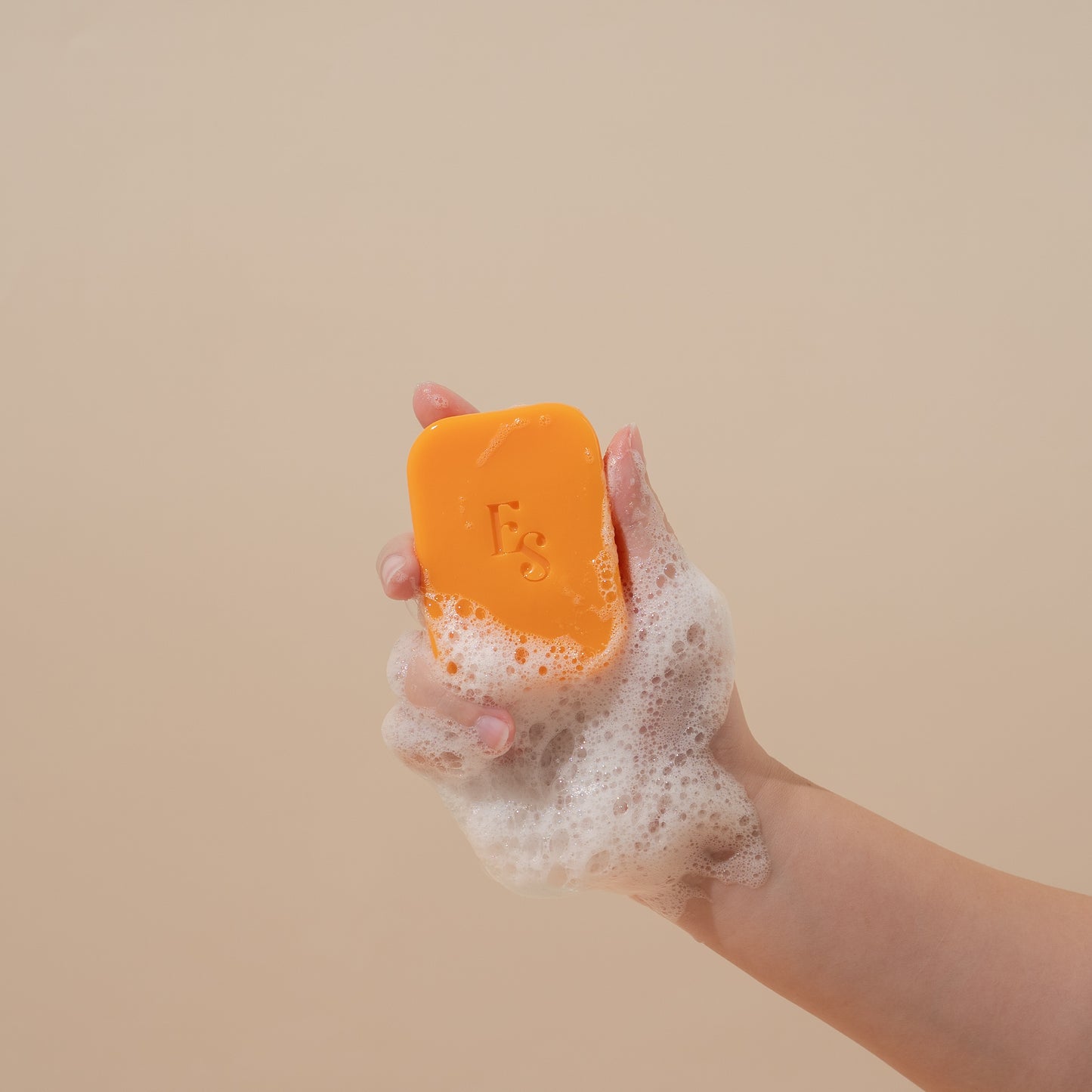 Orange Radiance Soap by Elyesence held in hand with foamy lather
