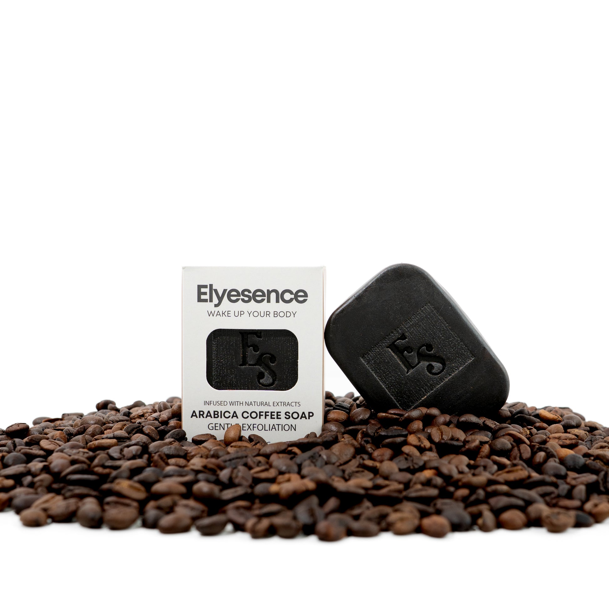 Elyesence Arabica Coffee Soap bar and packaging resting on a bed of roasted coffee beans, highlighting its natural exfoliating ingredients.