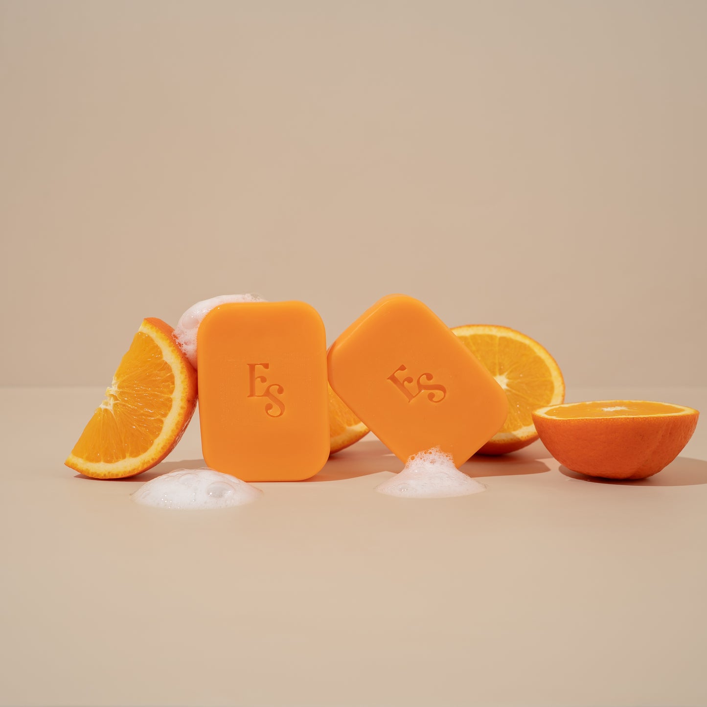 Two Orange Radiance Soap bars surrounded by orange slices and bubbles